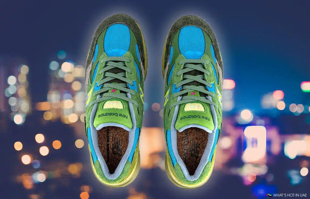 Green and blue Salehe Bembury x New Balance 992 sneakers with New Balance branding, set against a cityscape with blurred lights.