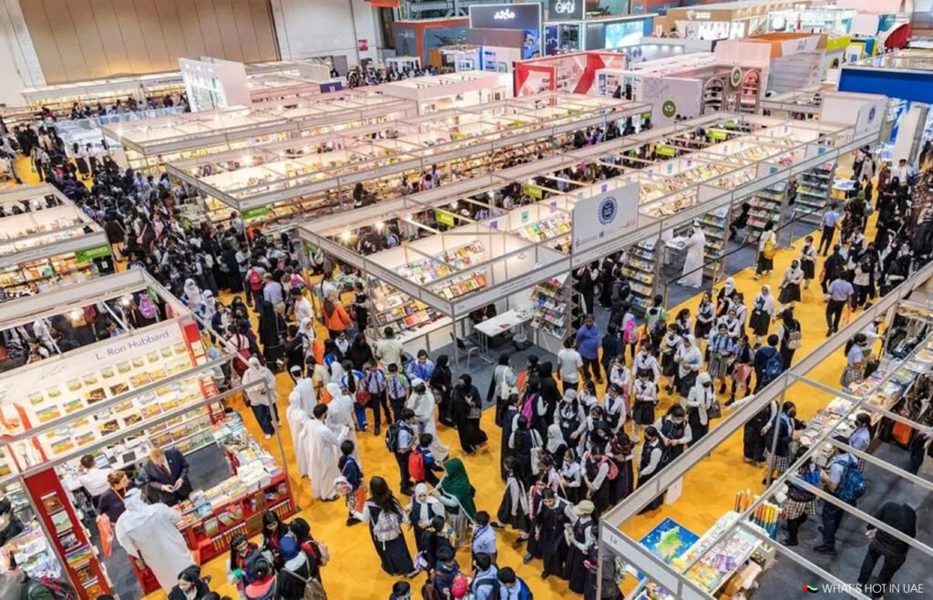 Large crowd attending a busy Sharjah International Book Fair 2027, with numerous stalls displaying books and people walking around.