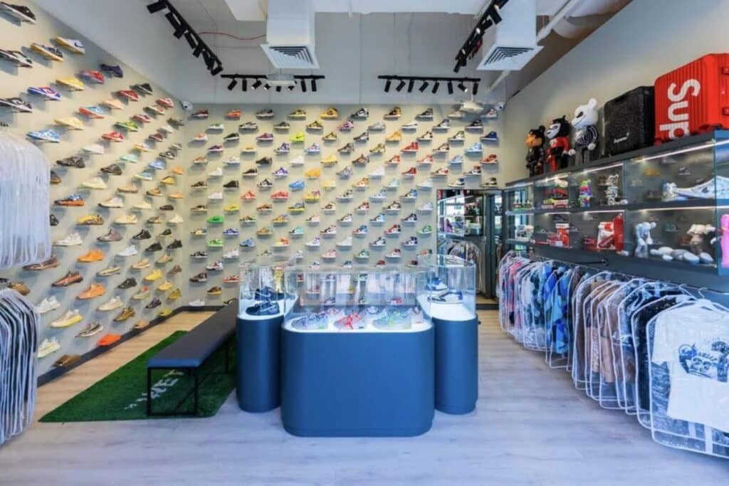 A Dubai Essential Sneaker Stores shop with sneakers displayed on a wall, glass cases with merchandise, and clothing hung on racks.