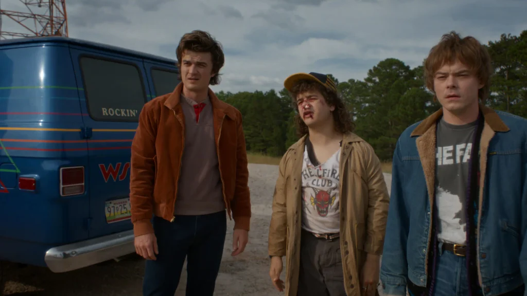 The characters from Stranger Things 5 standing next to a blue truck