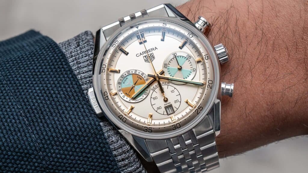 A TAG Heuer Carrera Seafarer wristwatch with a white and blue dial, featuring a chronograph and date functions, worn on a wrist with a blue jacket sleeve.