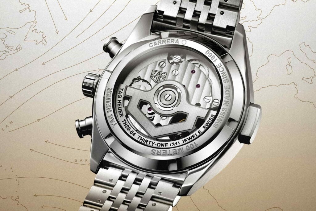 A close-up of a TAG Heuer watch back, showing its intricate mechanical movement and metal bracelet on a map-like background.