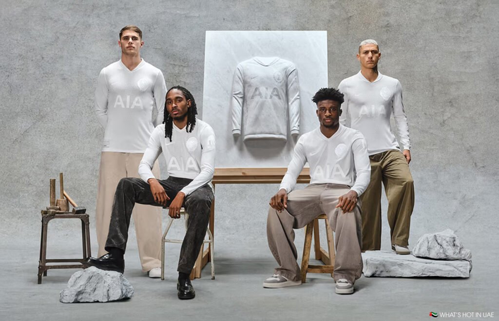 Four men pose around a sculpted art piece featuring a white football jersey with a rock-like texture backdrop.
