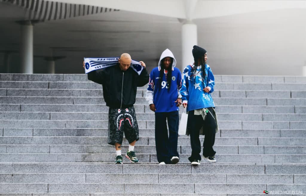 Three people wearing eclectic streetwear walk down concrete steps, each showcasing unique fashion styles.