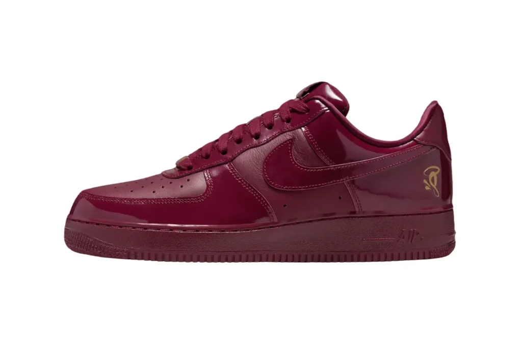 A Nike Air Force 1 Low 'Dark Beetroot' sneaker with a glossy finish, featuring a Nike Swoosh and a small gold graphic on the heel.