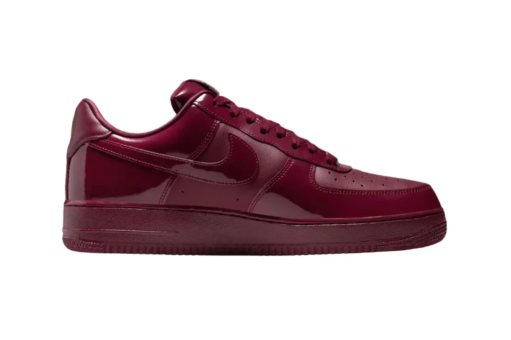 A maroon sneaker with glossy finish and a prominent swoosh logo on its side.