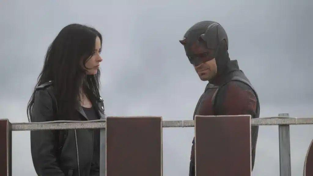 Daredevil: Born Again Season 2: Two characters stand on a rooftop; one wears a red and black superhero suit with a mask, the other in a black leather jacket.