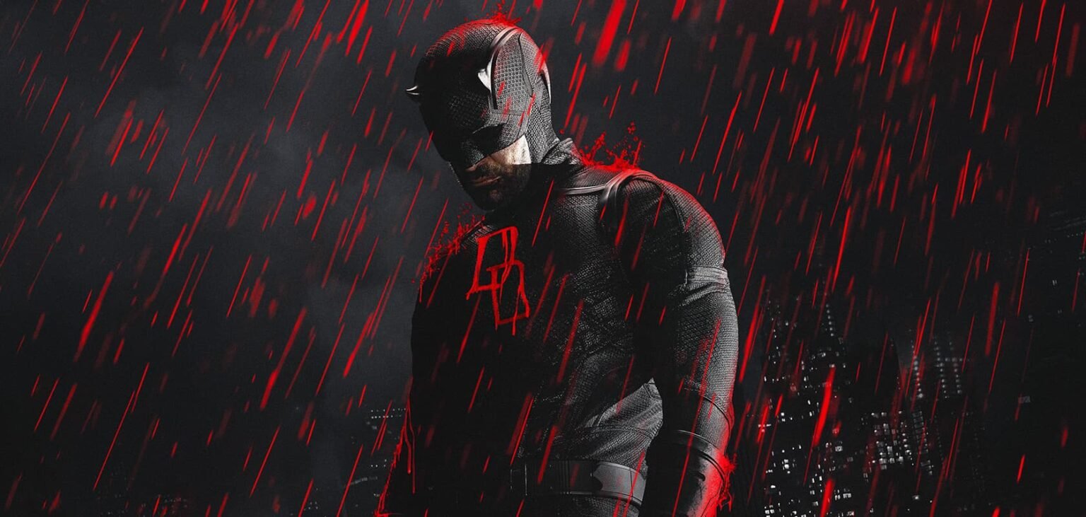 A superhero in a dark suit with horns and a red emblem stands under red rain against a cityscape.