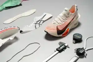 A modern running shoe with various components like insoles, outsoles, and tools for precision measurement displayed around it.