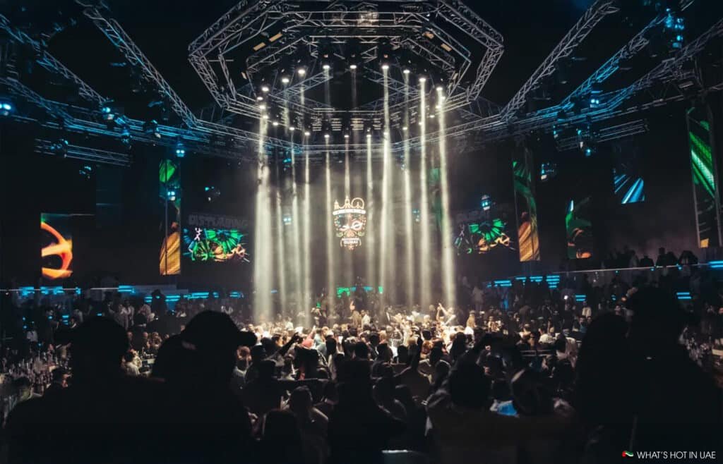 A crowded nightclub with colorful stage lights and a lively atmosphere.
