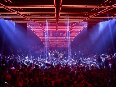 A crowded nightclub with vibrant red and blue lights illuminating the dance floor.