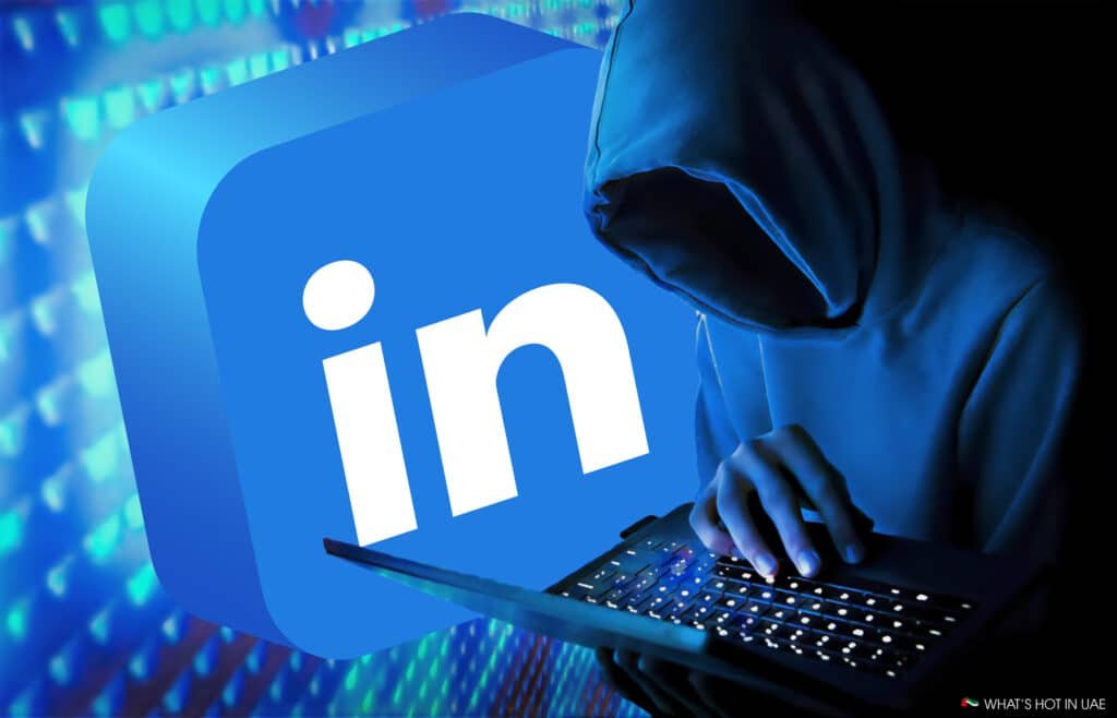 A person in a hooded sweatshirt uses a laptop, with a large LinkedIn logo in the background.