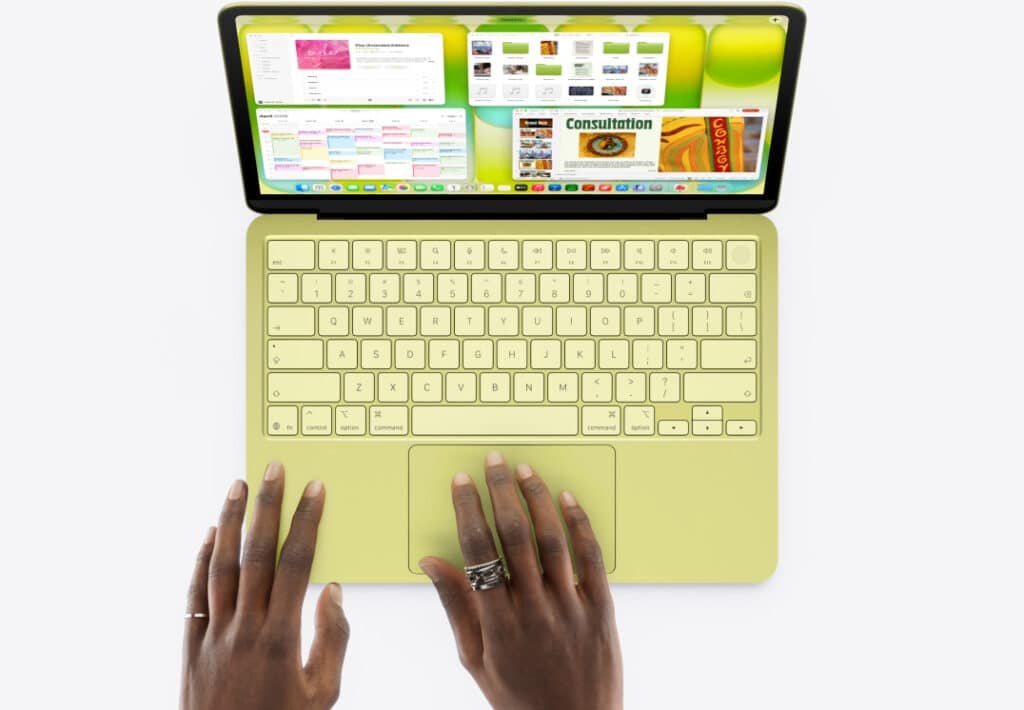 A person typing on a yellow laptop with multiple apps open on the screen.