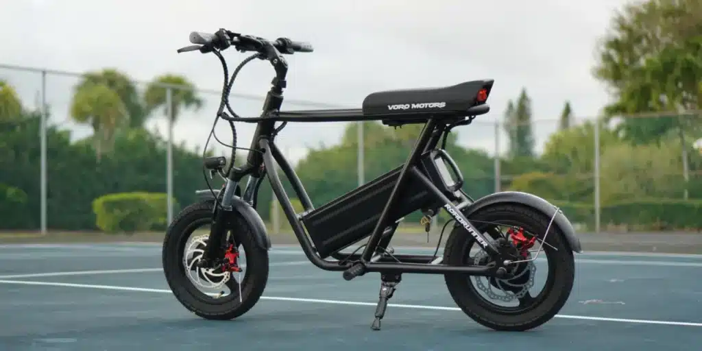 Electric bicycle with a sleek black frame, wide tires, and visible Voro Motors branding on a tennis court.