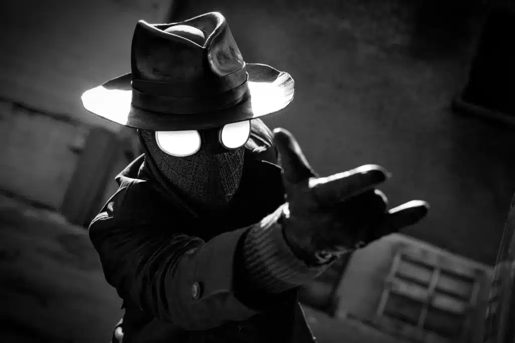Spider-Noir Series in a fedora and mask, with glowing eyes, striking a dynamic pose in a shadowy setting.