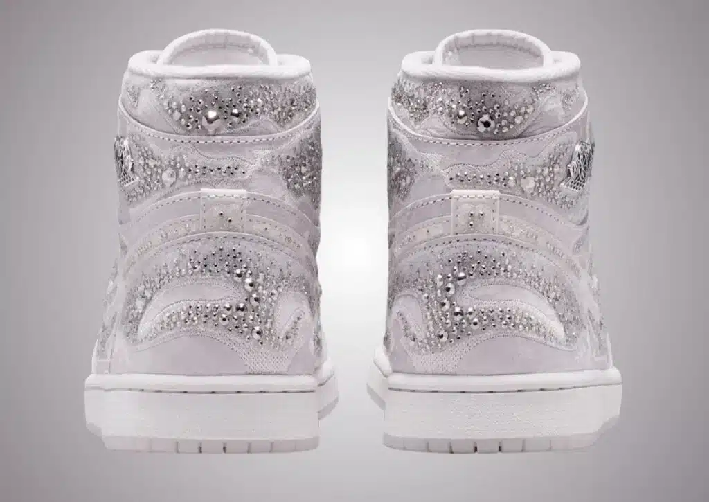 Pair of white high-top sneakers embellished with silver studs and rhinestones, viewed from the back.