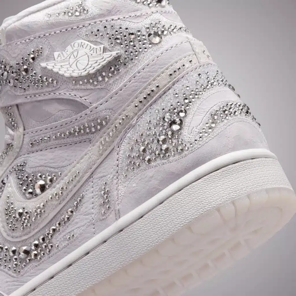 A white sneaker with intricate crystal embellishments, featuring the Air Jordan logo on the side.