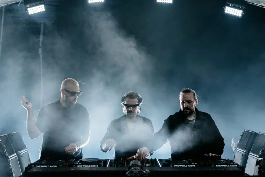 Dubai Nightlife Statistics 2026: Three DJs wearing dark clothing perform with DJ equipment on a smoky stage.