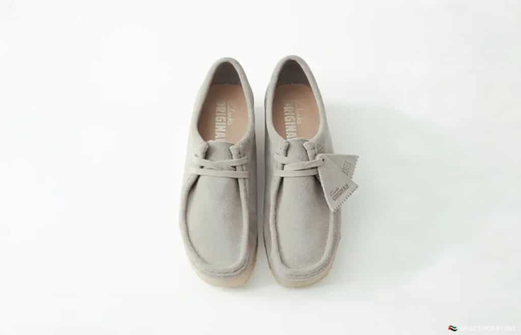 A pair of light gray suede desert boots with laces, displayed on a white background.