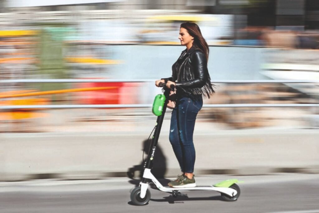 A woman with a Dubai E-Scooter Permit in a black jacket and jeans rides an electric scooter in an urban setting.