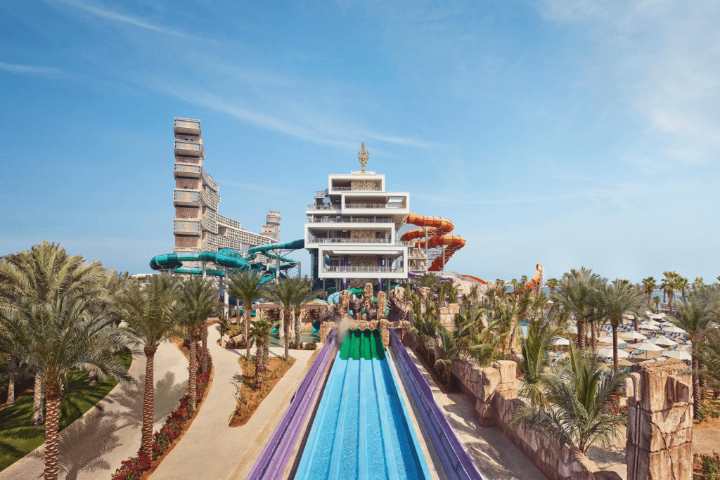 Aquaventure Waterpark with a tall central structure surrounded by colorful water slides and pools, set in a landscaped area with palm trees.