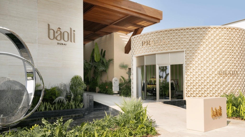 Exterior of Báoli Dubai, featuring a modern architectural design with geometric patterns, lush greenery, and a sleek metal sculpture.
