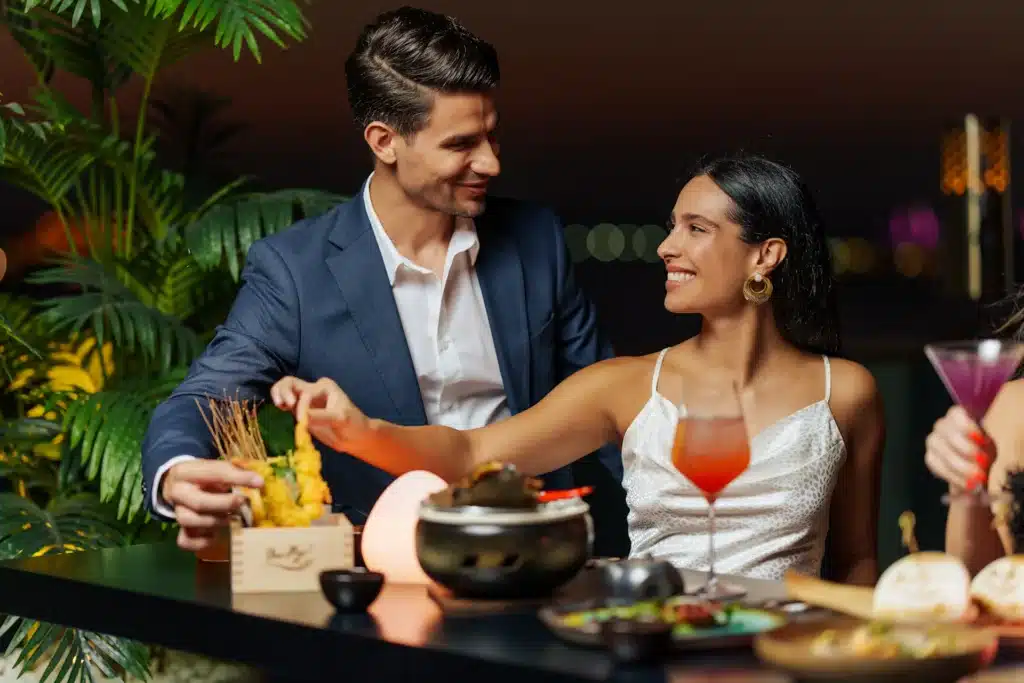 Dubai Best Sushi Restaurants:  Barfly. A couple enjoying a meal together at a stylish restaurant, with assorted dishes and drinks on the table.