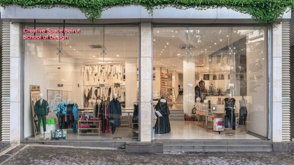 Storefront with large glass windows displaying clothing and accessories; sign reads "Creative Space Beirut School of Design."