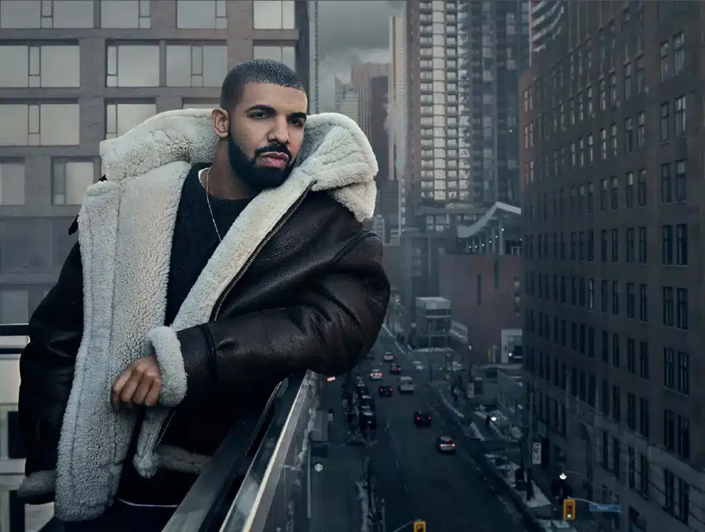 A person in a shearling jacket leans against a railing, overlooking a city street with tall buildings.