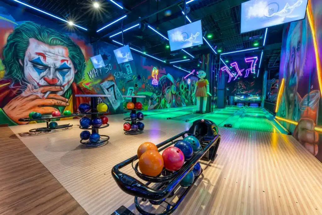 Colourful Dubai bowling center with vivid graffiti art, including a clown face, and bright neon lights illuminating the lanes.