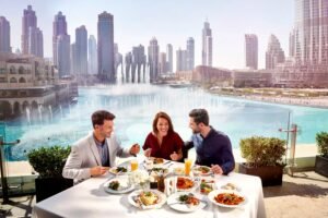 Three people enjoy a meal at an outdoor table overlooking a city skyline and large fountain.