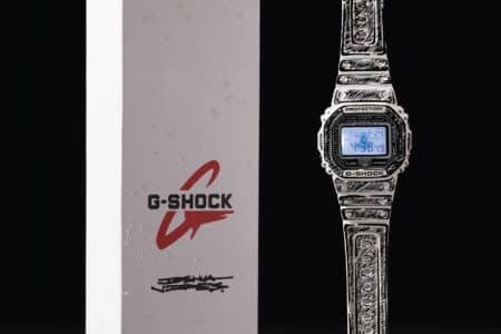 A patterned G-Shock watch with a digital display next to branded packaging with logo.