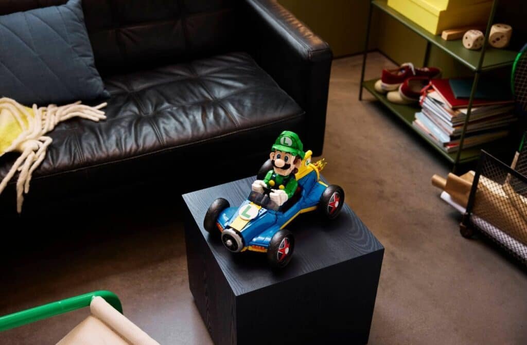 A Luigi toy in a go-kart sits on a black pedestal in a cozy living room setup.