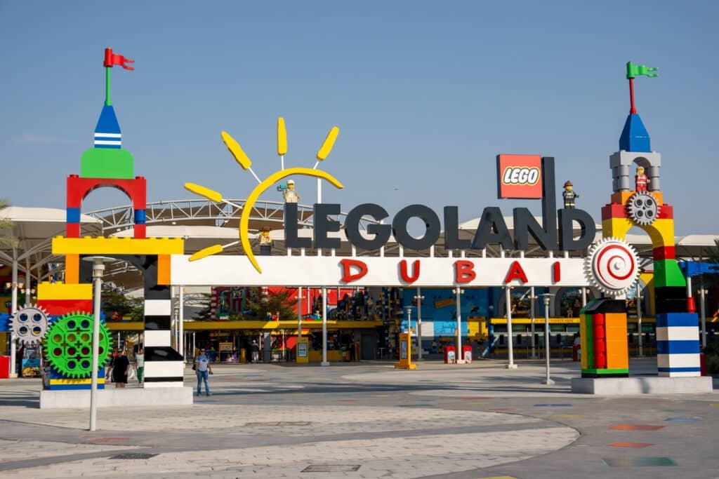 Entrance to Legoland Dubai with colorful Lego structures and a large sun motif above the sign.