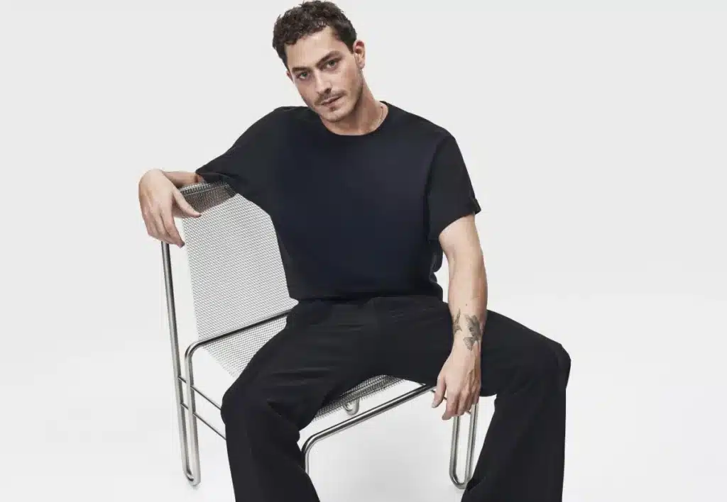 Support Lebanese Brands: Empowering Resilience, Craftsmanship, and Community from the UAE: A person in a black outfit sits on a modern metal chair against a plain white background.