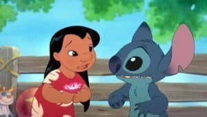 A girl in a red dress holds a flower while standing next to a blue alien creature in a setting with trees and a wooden fence.