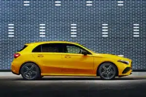 A bright yellow hatchback car parked in front of a patterned brick wall.
