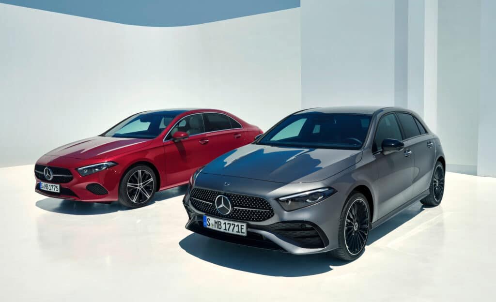 Two parked Mercedes-Benz cars, one red and one gray, on a sunlit, minimalist white surface with walls.
