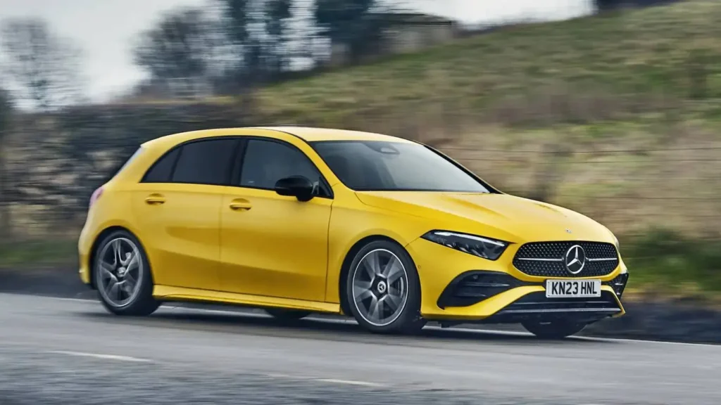 A yellow hatchback car with sleek design driving on a wet road.