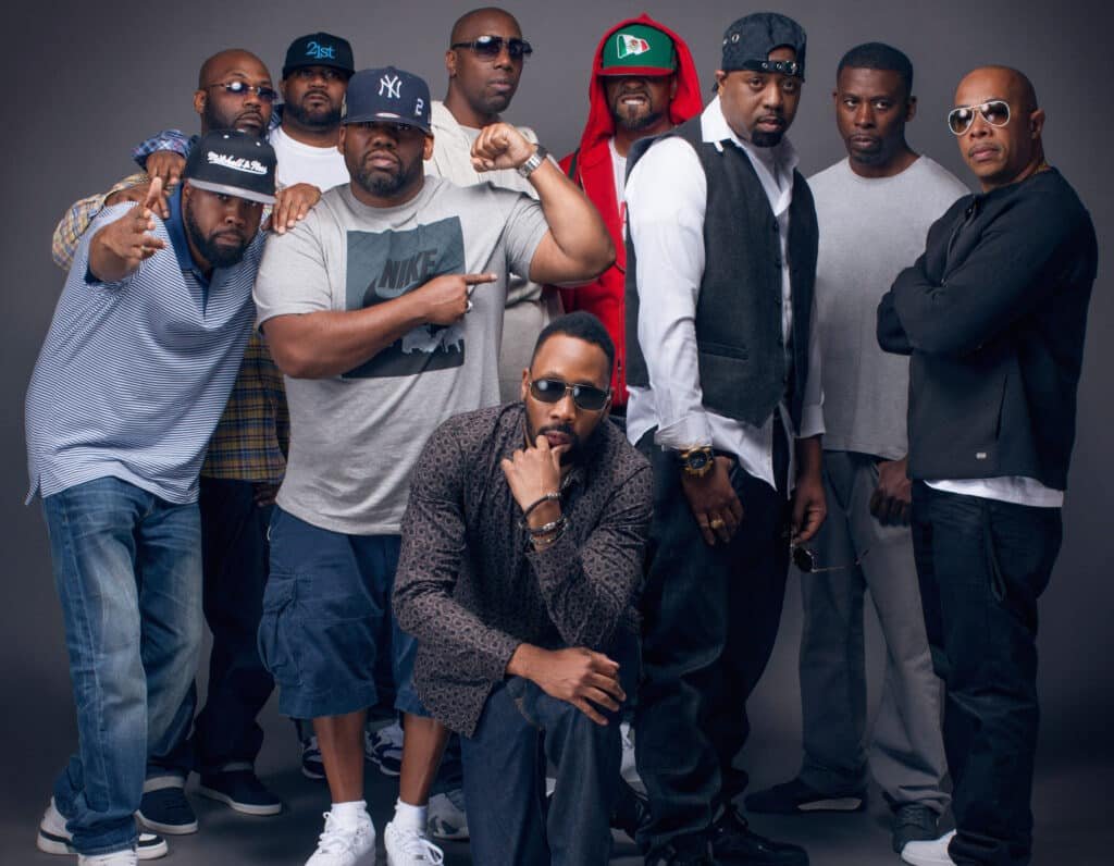 Wu Tang Clan posing together, some wearing hats and sunglasses, against a plain background.