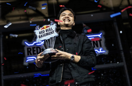 A person holding a Red Bull Basement trophy, smiling, with confetti falling around them.
