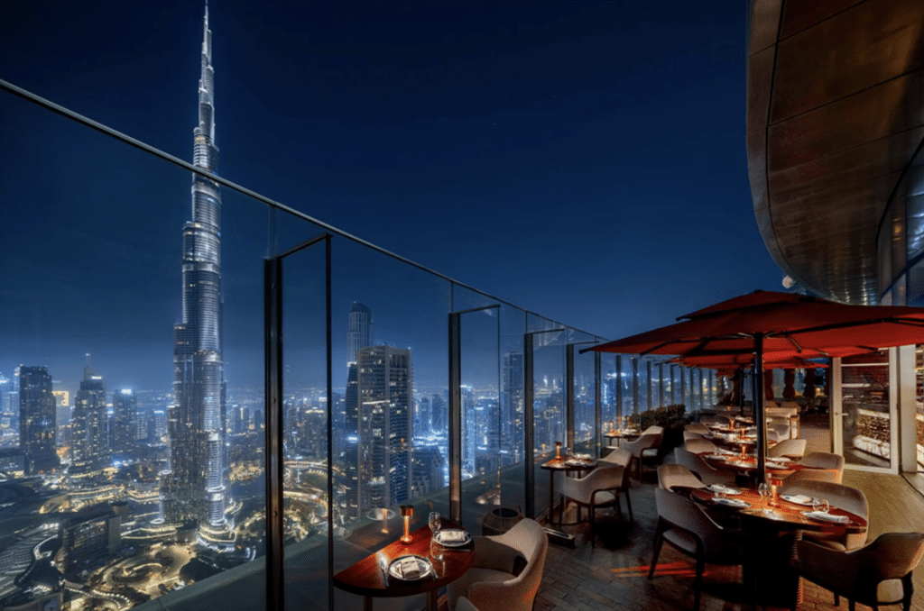 A rooftop restaurant at night with a view of the illuminated Burj Khalifa and cityscape.