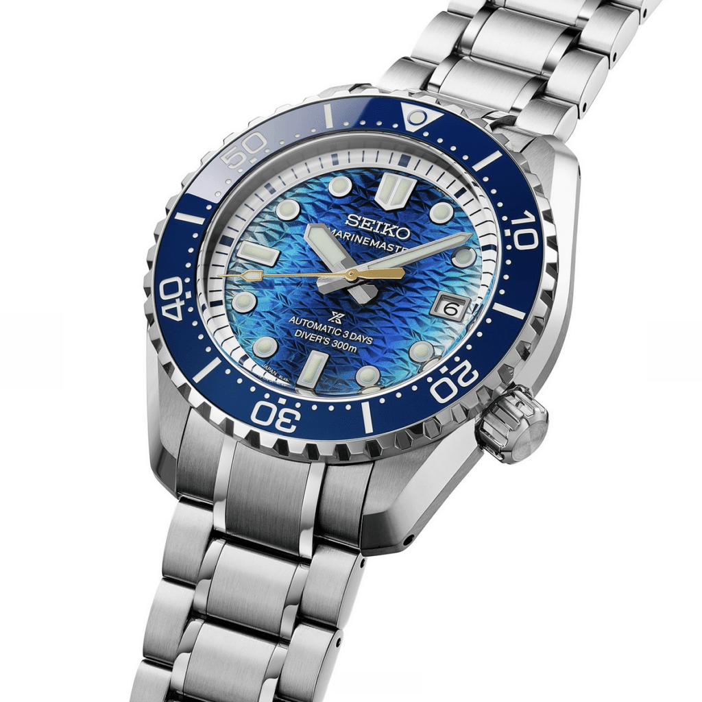 A Seiko Prospex Marinemaster diver's watch with a silver metal band and a blue wave-patterned dial featuring bold indices and a date display.