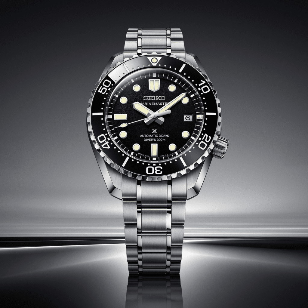 A silver Seiko Prospex Marinemaster diving watch with a black dial, luminous markers, and a stainless steel bracelet, displayed against a sleek background.
