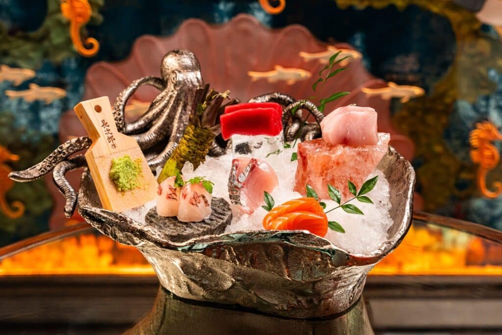 A beautifully presented seafood platter with various sashimi, ice, garnishes, and an ornate octopus decoration.