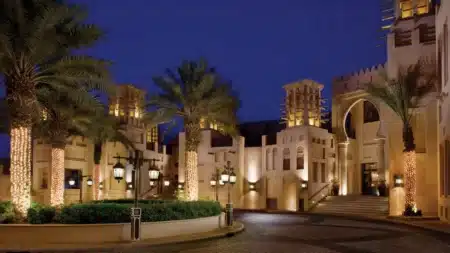A luxurious hotel entrance with palm trees and warm lighting at dusk.