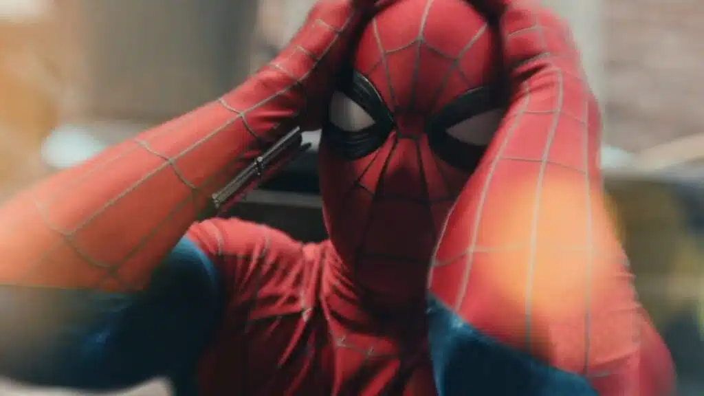 Superhero in red and blue costume with web patterns holds head in a frustrated pose.