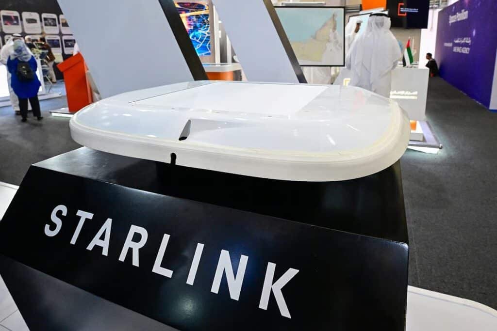 Starlink satellite dish display in a tech exhibition booth with a map and attendees in the background.