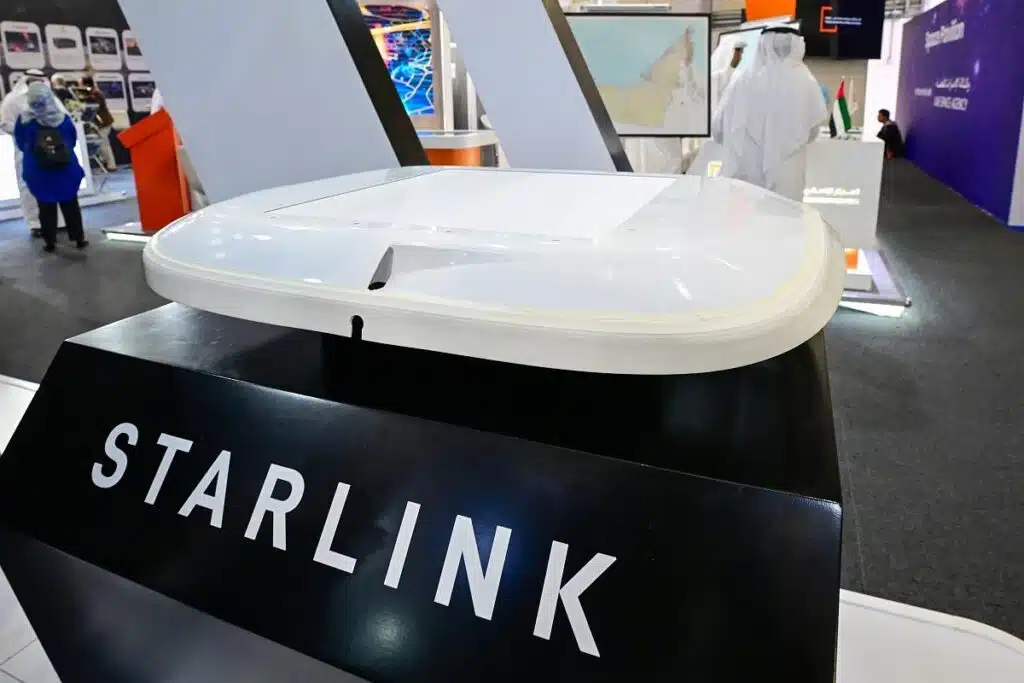 Starlink satellite dish display in a tech exhibition booth with a map and attendees in the background.