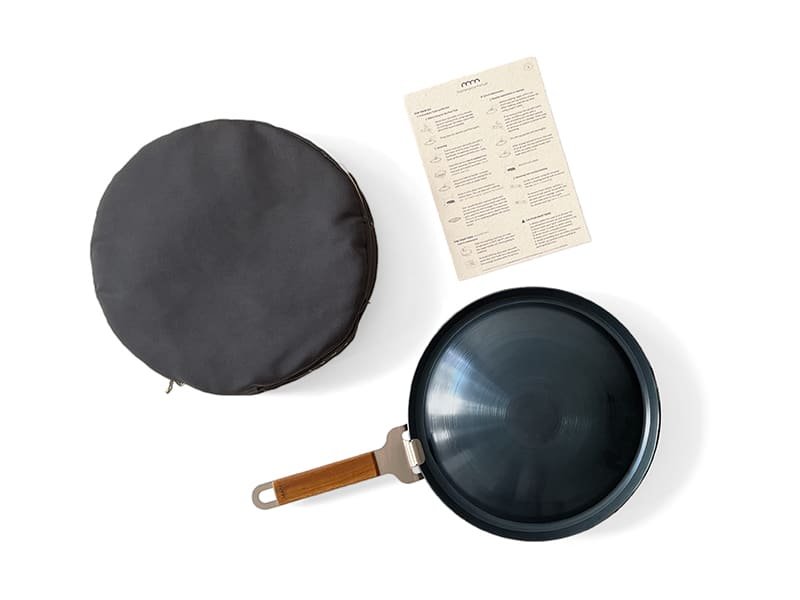 A black frying pan with a wooden handle, a circular black case, and an instruction sheet on a white background.